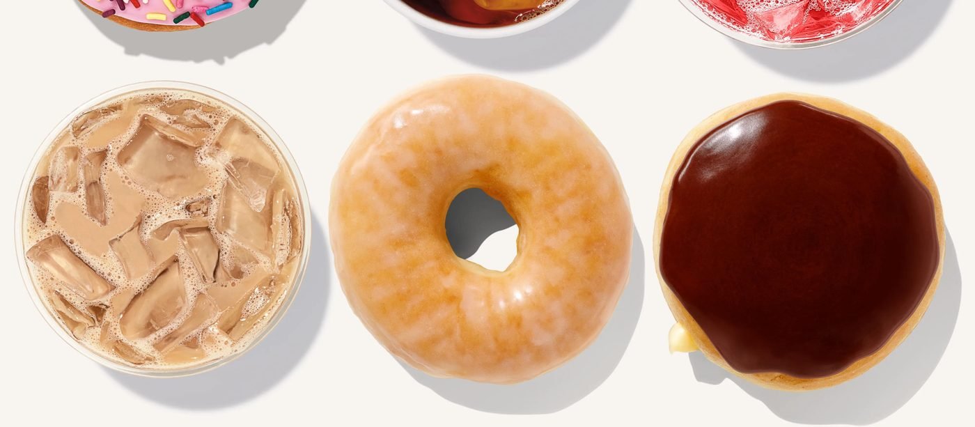 Overhead spread of Dunkin' donuts and iced coffee: an iced latte, a glazed donut and a chocolate-frosted donut